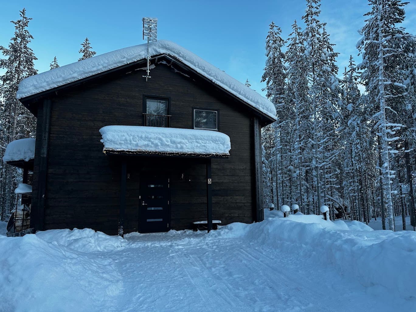 The Snow & Pine log cabin under deep snow at blue hour, surrounded by private forest in Levi