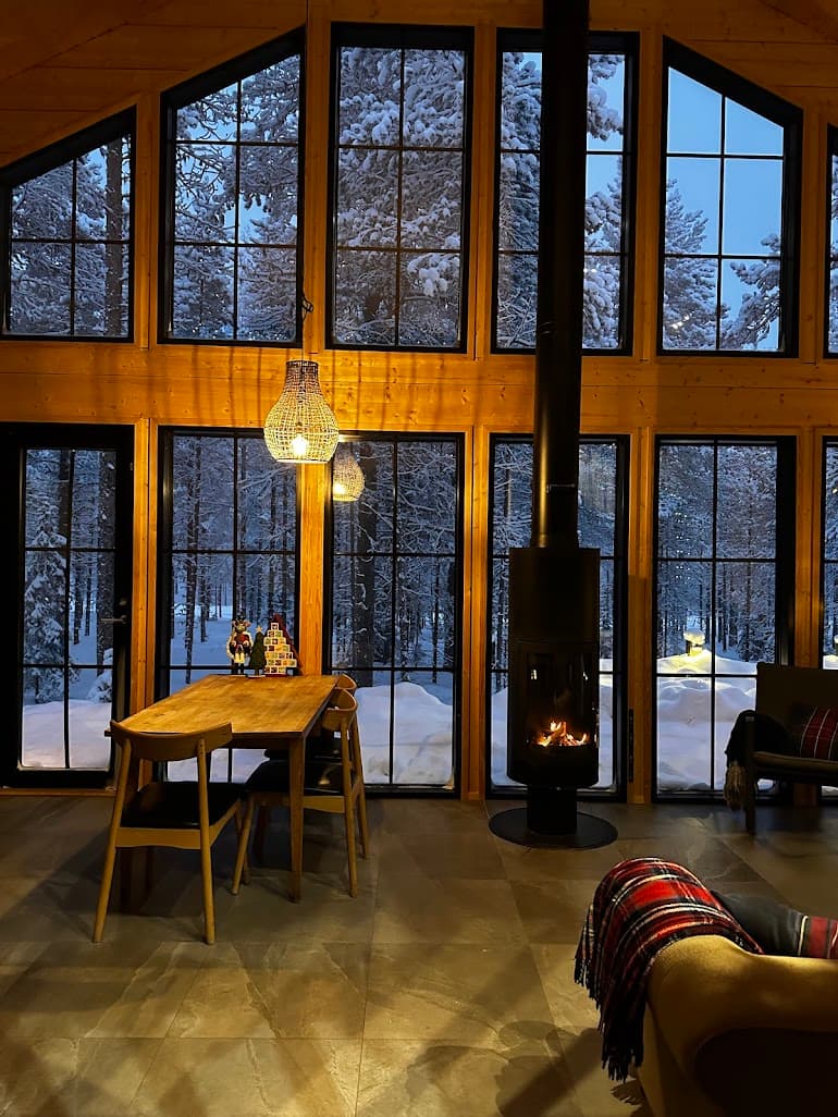 Interior of Snow & Pine cabin at dusk — floor-to-ceiling glazing onto the Levi forest